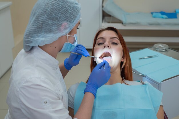 Woman dentist checking her patient for caries Redhaired woman examined by a doctor The girl will do the health of the teeth