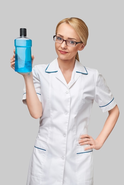 Woman dentist doctor holding bottle of mouthwash