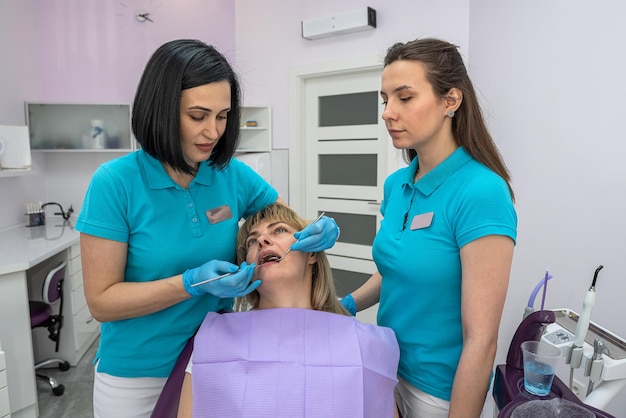 A woman dentist and her assistant in examine the teeth of a woman who came to the reception