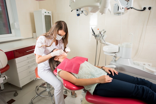 Woman dentist in her office treating female patient