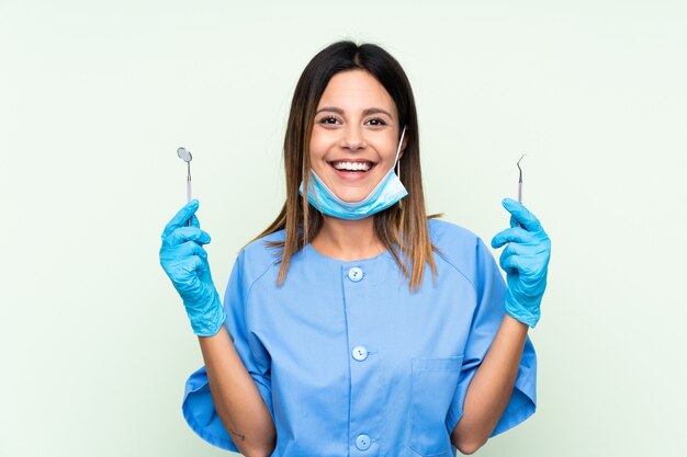 Woman dentist holding tools over green wall