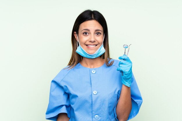 Woman dentist holding tools having doubts and with confuse face expression