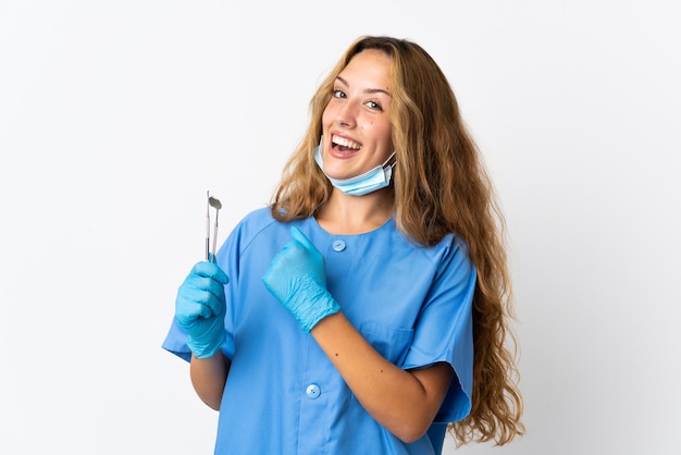 Женщина-стоматолог держит инструменты, изолированные на белой стене, празднует победу