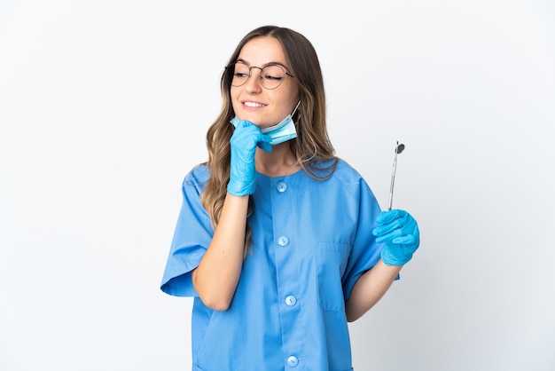 Woman dentist holding tools posing isolated against the blank wall