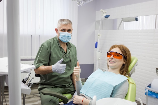 Woman and dentist showing thumb up sign at office clinic