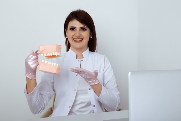 Dentista della donna che si siede alla tavola in ufficio con personale dentale isolato.