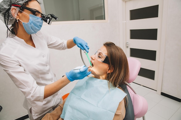 Woman dentist treats teeth of a young woman lying in the clinic. doctor treats teeth.