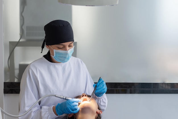 Woman dentist in uniform and face mask during a dental intervention on a woman Dental clinic concept