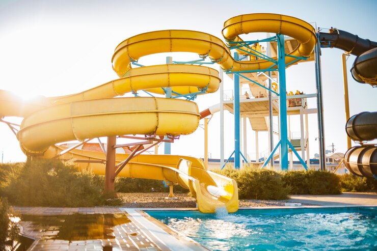 Photo an woman an descended from a large high yellow slide into a pool created spray
