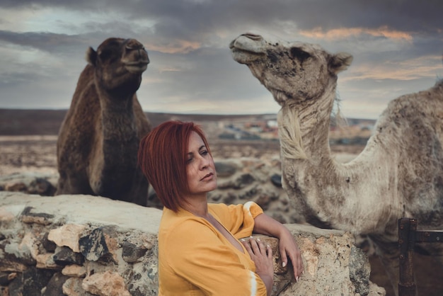 woman in a desert landscape with camels