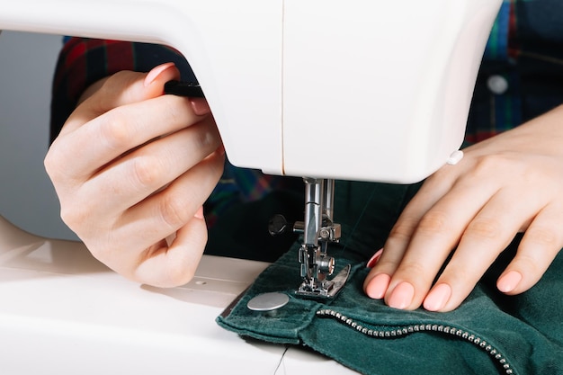 Фото Женщина-дизайнер или портной, работающая на швейной машине руки держат и шиют детали одежды всемирный день портных близкий план процесса шитья человек