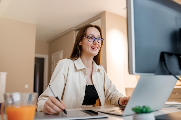 Woman designer working at home office on new ideas Young happy female freelancer working on project watching movie on computer studying blogging resting and chatting online