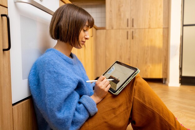 Woman Designing Kitchen Interior On A Digital Tablet At Home