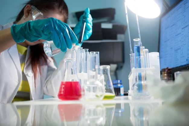 Woman at desk with laboratory test tubes, flasks