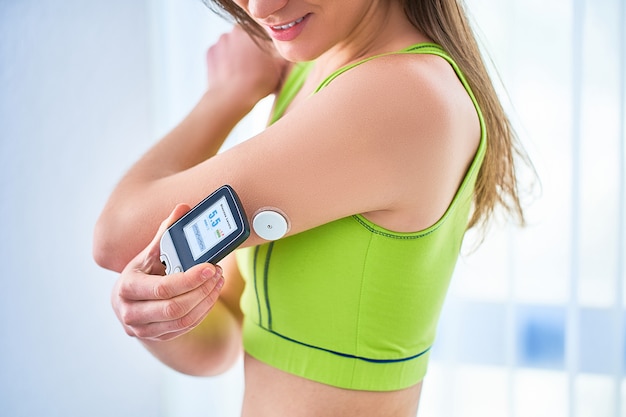 Woman diabetics control and checking glucose level with a remote sensor. Monitoring glucose levels without blood. Technology in diabetes treatment. Healthcare and medicine