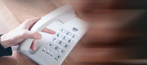 Una donna compone un numero su un telefono cablato di casa