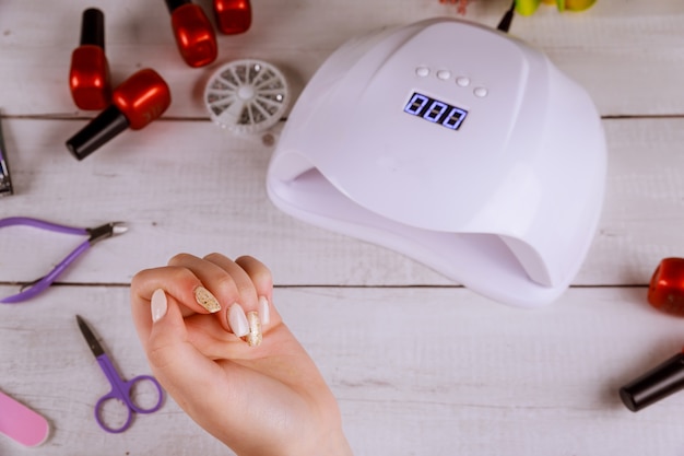 Woman did beautiful acrylic manicure with led lamp