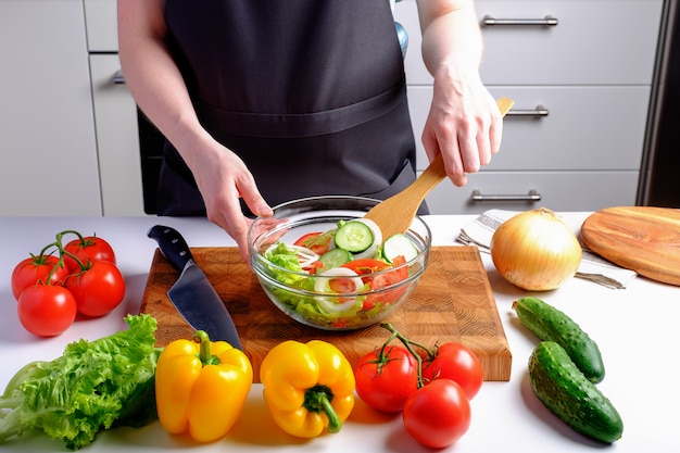 Woman on diet cooking salad from fresh vegetables