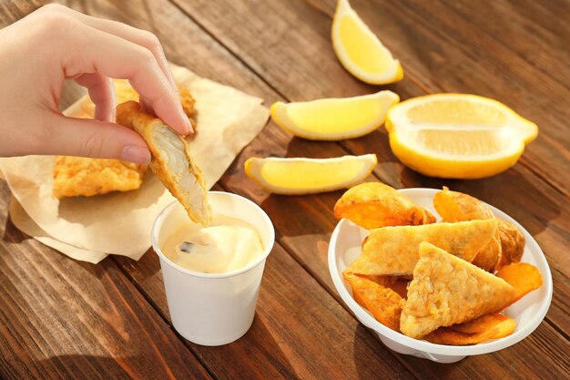 맛있는  ⁇ 긴 생선 한 조각 을 소스 클로즈업 에 담그고 있는 여자