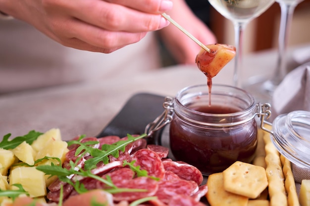 Woman dips parmesan cheese into sauce Two glasses of white wine and Italian antipasto meat platter