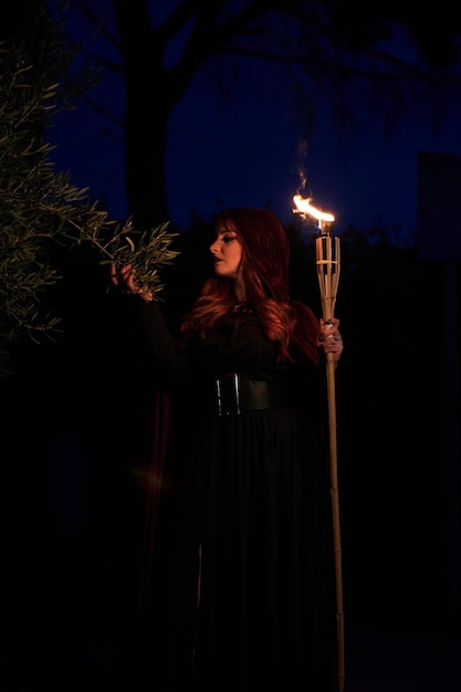 Foto donna travestita da strega con in mano una torcia fiammeggiante