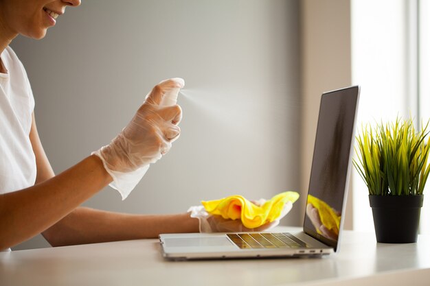 Woman disinfect laptop by wet wipes and antiseptic