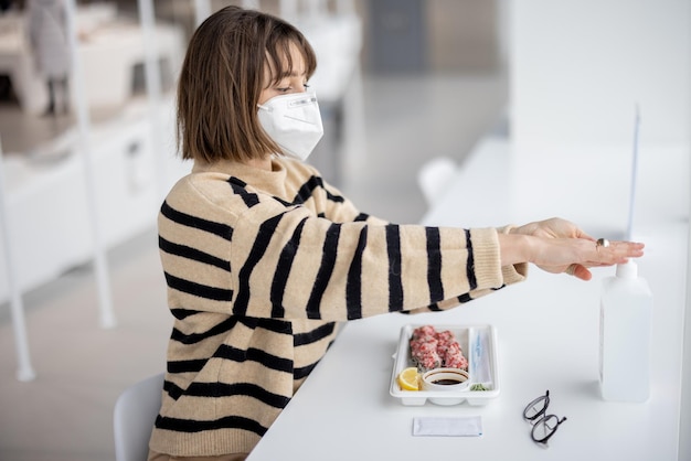 Woman disinfects hands with sanitizer ar restaurant