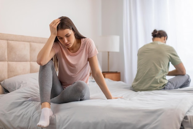 Woman distressed on bed man with back turned