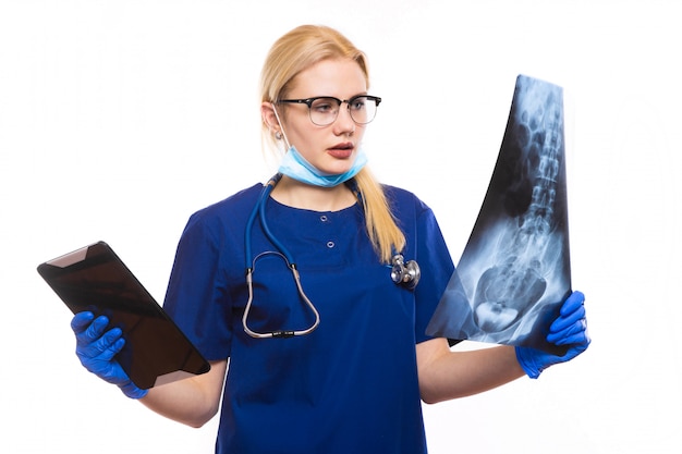 Woman doctor in blue scrubs studies X-ray with pc