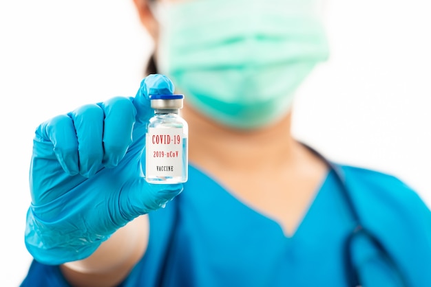 Woman doctor in blue uniform holding covid-19 vaccine