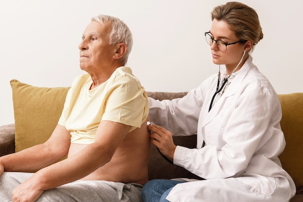 Woman doctor checking up health conditions of elderly man