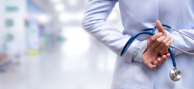 Woman doctor crossed arm and holding stethoscope behind back on blurred background