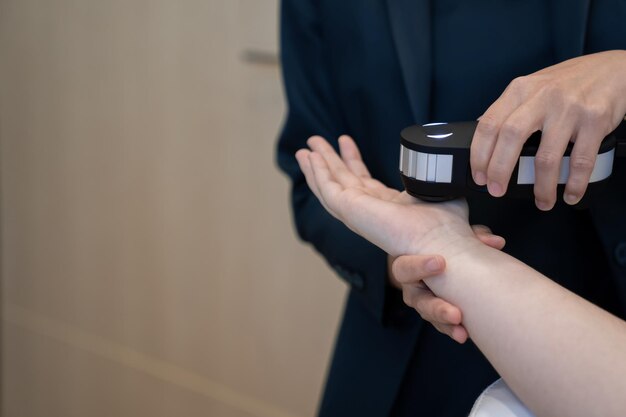 Woman doctor in a dark uniform suit is testing a patient's hand for her health statistic that show on the laptop monitor