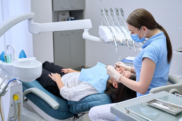 Woman doctor dentist treating teeth to patient in dental chair. Dental treatment, medicine dentistry and health care concept