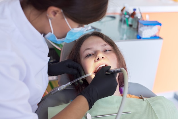 Woman doctor dentist treating teeth to woman patient in dental office