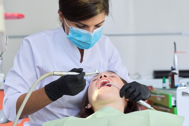 Woman doctor dentist treating teeth to woman patient in dental office