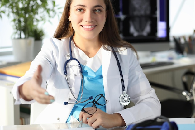 Woman doctor giving hand for handshake in clinic