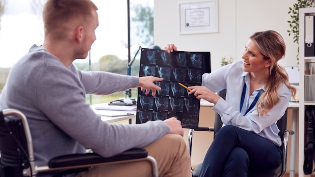 Woman Doctor Or GP In Office With Male Patient Looking At CT Or MRI Scan