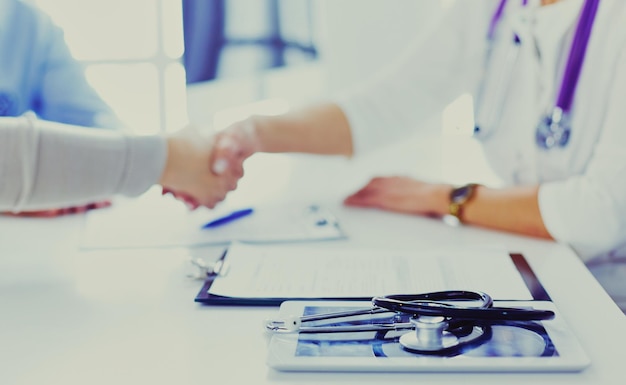 Woman doctor handshaking with a senior couple