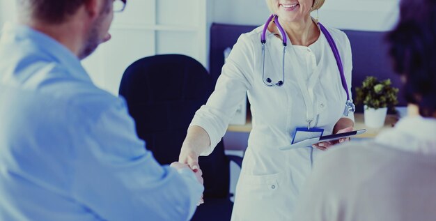 Woman doctor handshaking with a senior couple