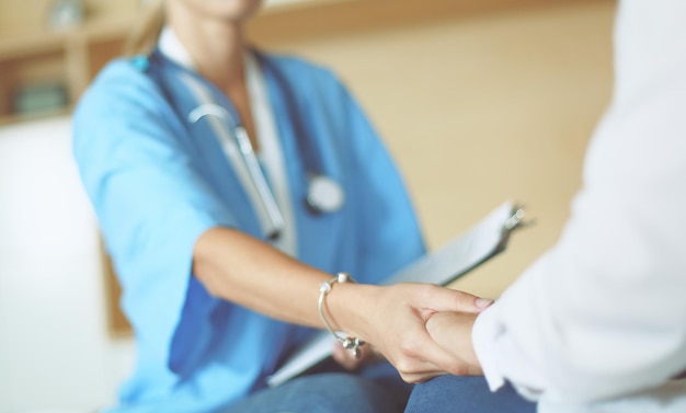 Woman doctor helping senior holding hand in hospital