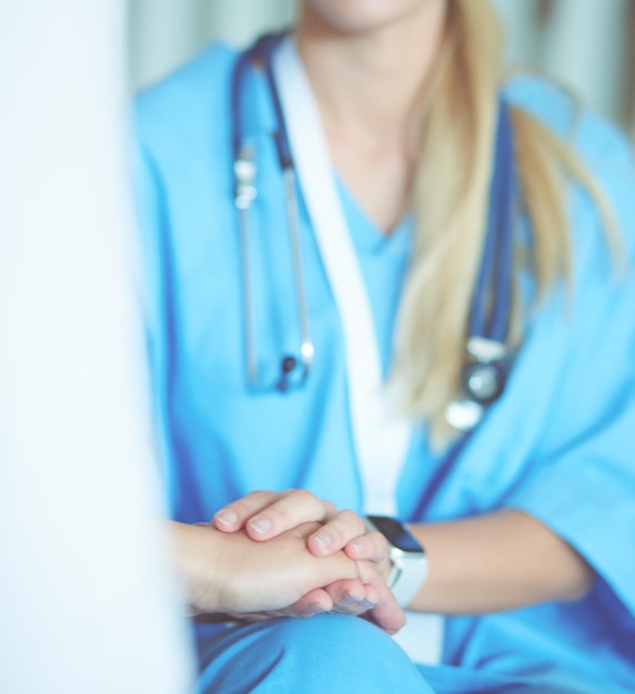 Woman doctor helping senior holding hand in hospital