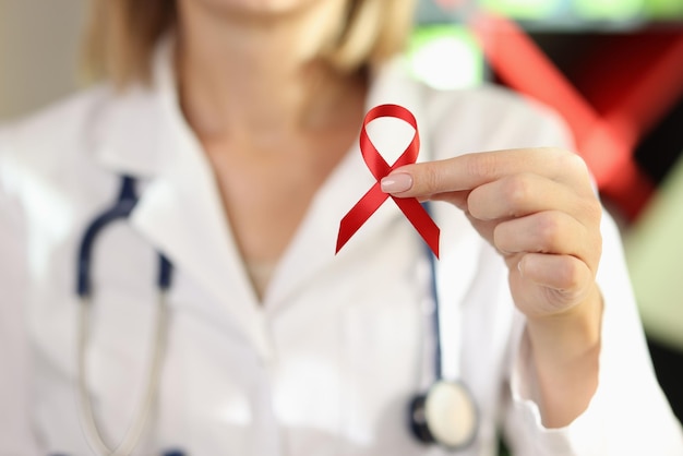 Woman doctor holding red ribbon as symbol of AIDS close up