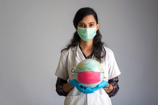 Woman doctor holding world globe with a medicine face mask. World epidemic of coronavirus concept.