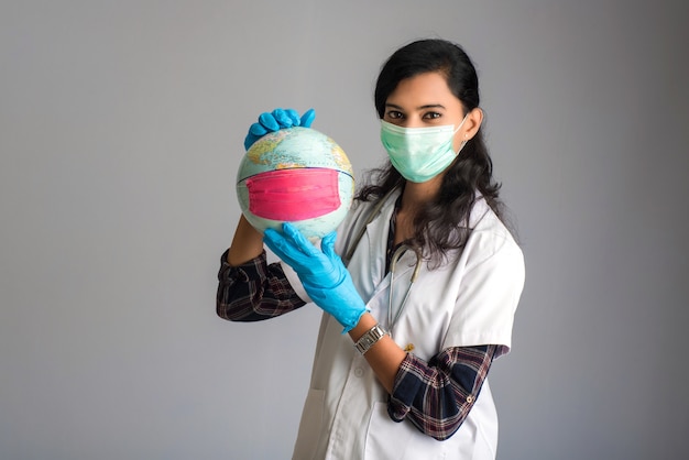 Woman doctor holding world globe with a medicine face mask. World epidemic of coronavirus concept.