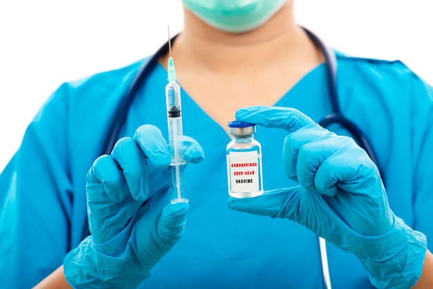 Женщина-врач в синей форме держит шприц и вакцину от covid-19