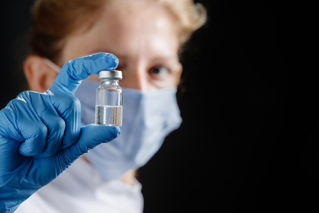 A woman doctor is holding a tube of medicine against a black background a nurse is holding a medicin