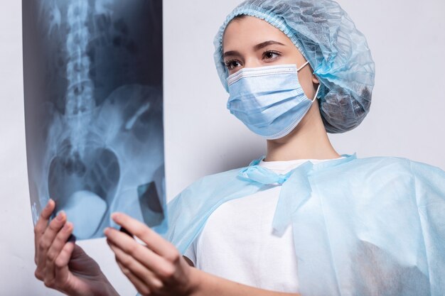 Woman doctor is holding an X-ray picture next to patient with kinesio tape on her knee. Injuries and sprains in athletes concept