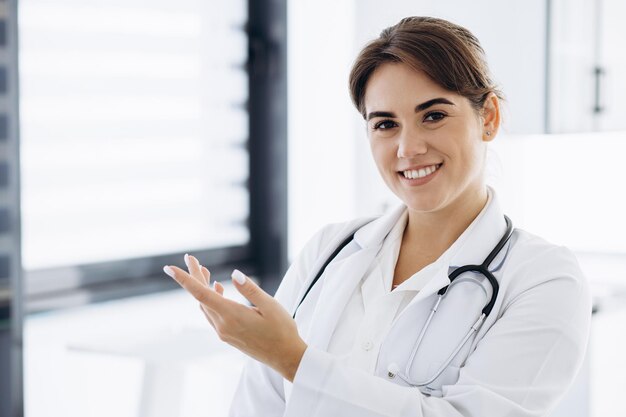 Woman doctor in lab coat with stethoscope pointing with finger