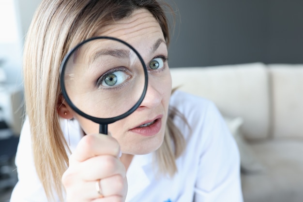 Woman doctor looking through magnifying glass closeup. Oncological search concept